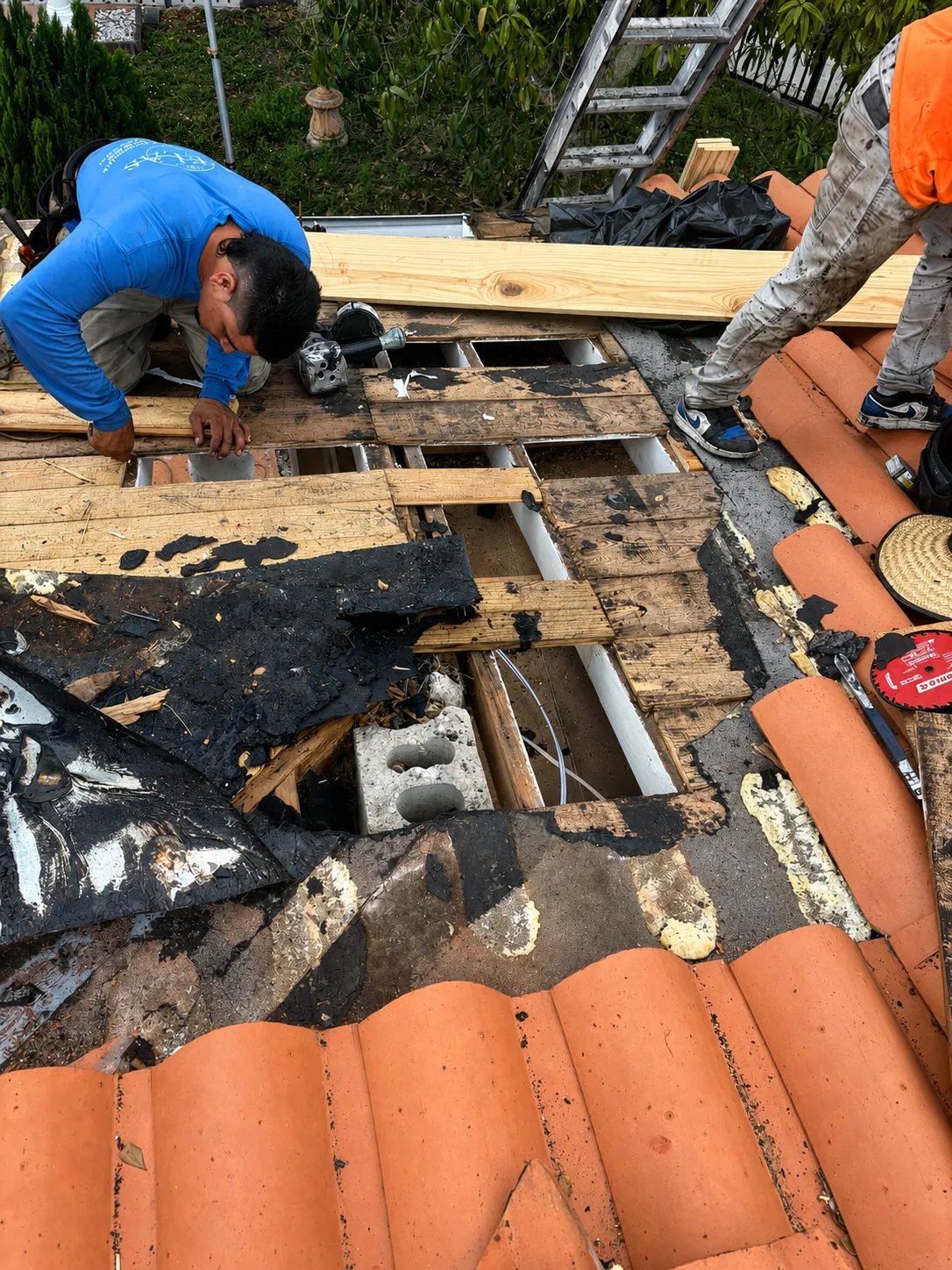 Equipo de Skymen Roofing reemplazando madera podrida bajo un techo de teja de barro